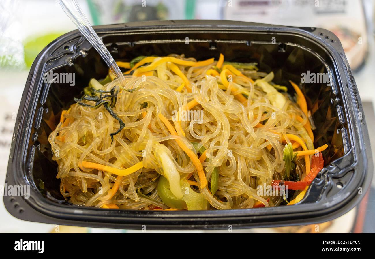 Noodle Japchae coreano con verdure. In un recipiente di plastica nero Foto Stock