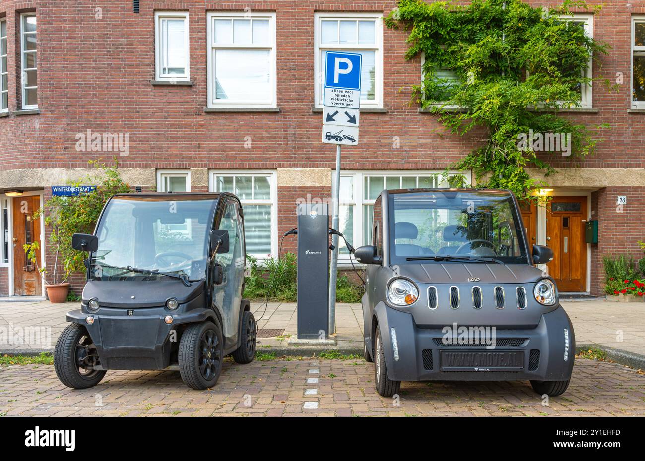 Amsterdam, Paesi Bassi, 28.08.2024, due piccoli veicoli elettrici vengono caricati presso il parcheggio della stazione di ricarica per veicoli elettrici Foto Stock