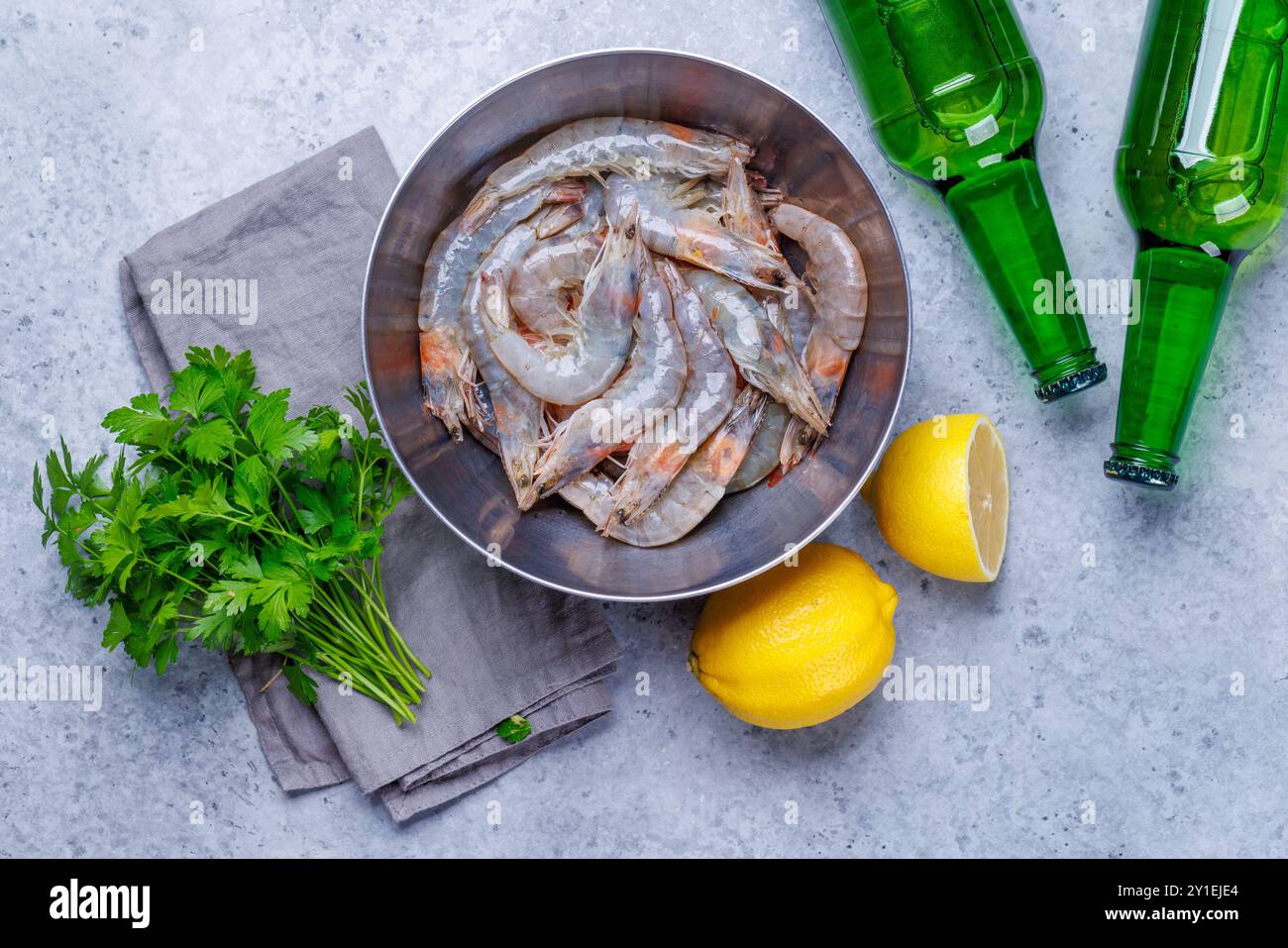 Gamberetti crudi freschi, accompagnati da rametti di prezzemolo fresco e limone succoso, pronti per la cottura. Spuntino con birra ideale Foto Stock