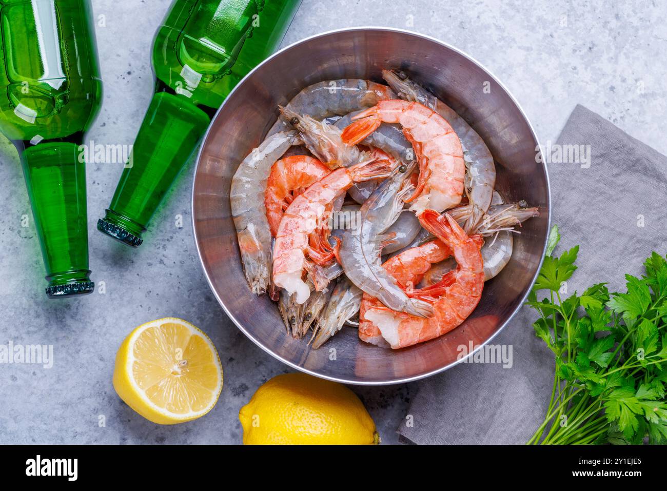 Gamberetti crudi freschi, accompagnati da rametti di prezzemolo fresco e limone succoso, pronti per la cottura. Spuntino con birra ideale Foto Stock