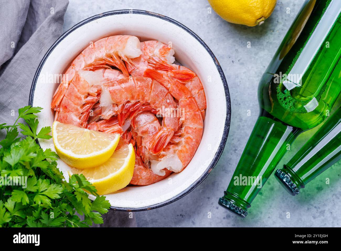Gamberetti crudi freschi, accompagnati da rametti di prezzemolo fresco e limone succoso, pronti per la cottura. Spuntino con birra ideale Foto Stock