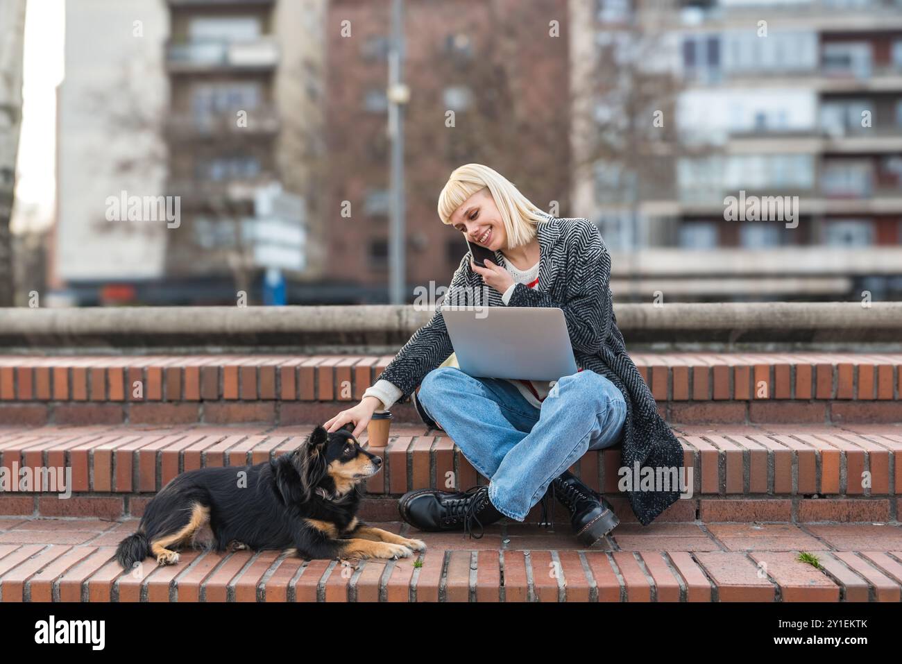 Giovane donna o ragazza adulta, studentessa universitaria, studentessa di scambio, freelance o espatriata che lavora su un laptop all'aperto con la sua adozione o il suo soccorso Foto Stock