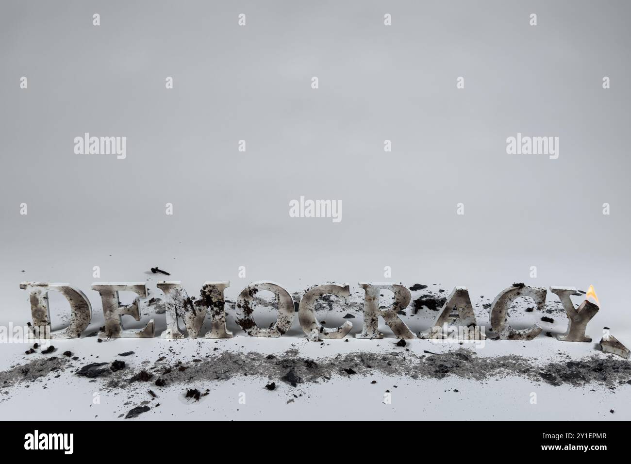 Le lettere di legno scrivono la parola democrazia su uno sfondo bianco. Le lettere sono bruciate e fangose, indicando che la democrazia è sotto attacco. Foto Stock