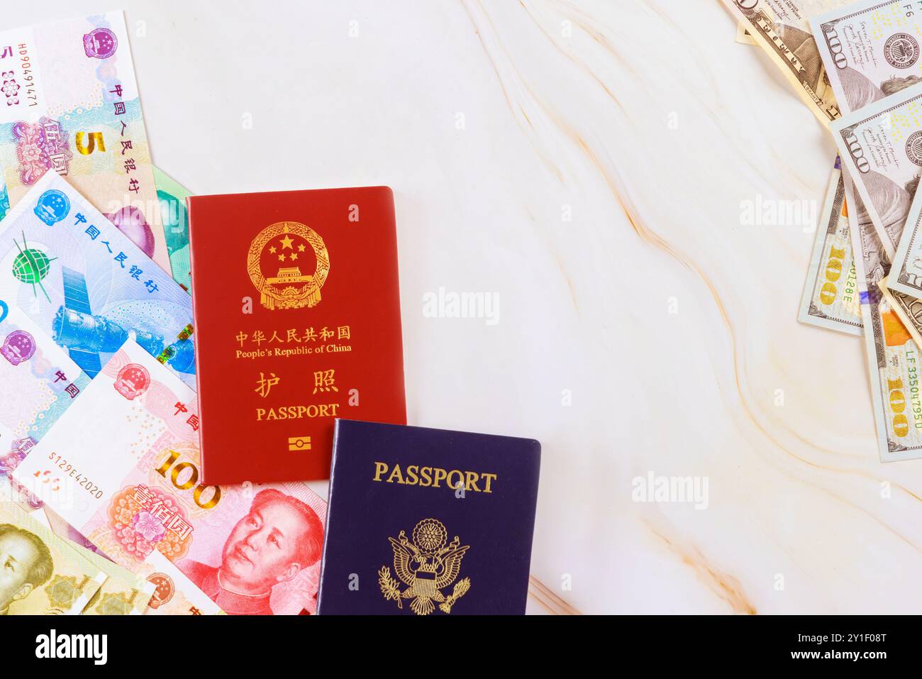 Passaporti provenienti dalla Cina, dagli Stati Uniti con yuan in contanti cinese, banconote in dollari statunitensi di vari tagli simboleggiano il confronto tra le economie di due nazioni Foto Stock