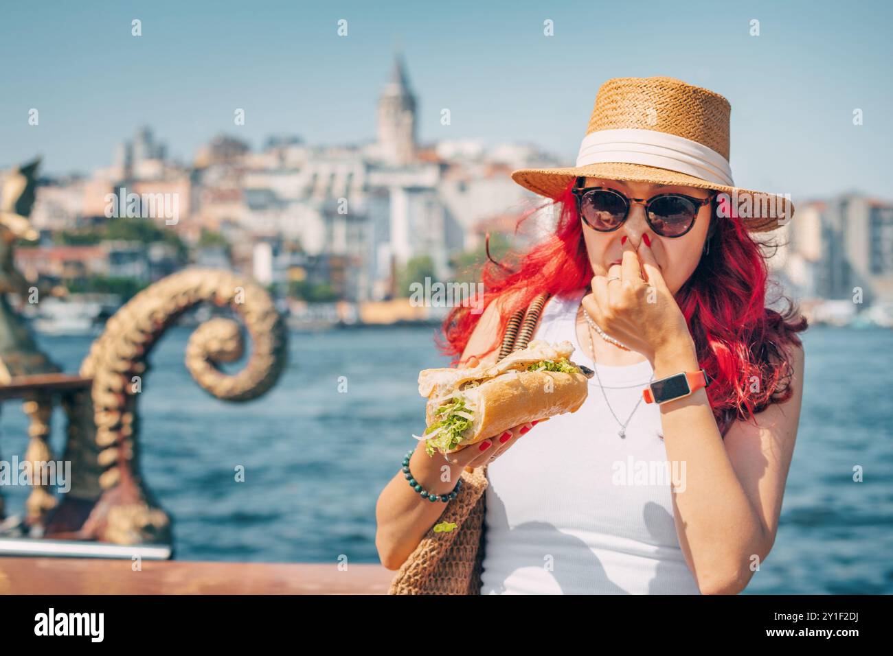 Una persona rinculica da un pasto di cibo di strada balik ekmek, esprimendo disprezzo e malsana condizione del panino di pesce. Foto Stock