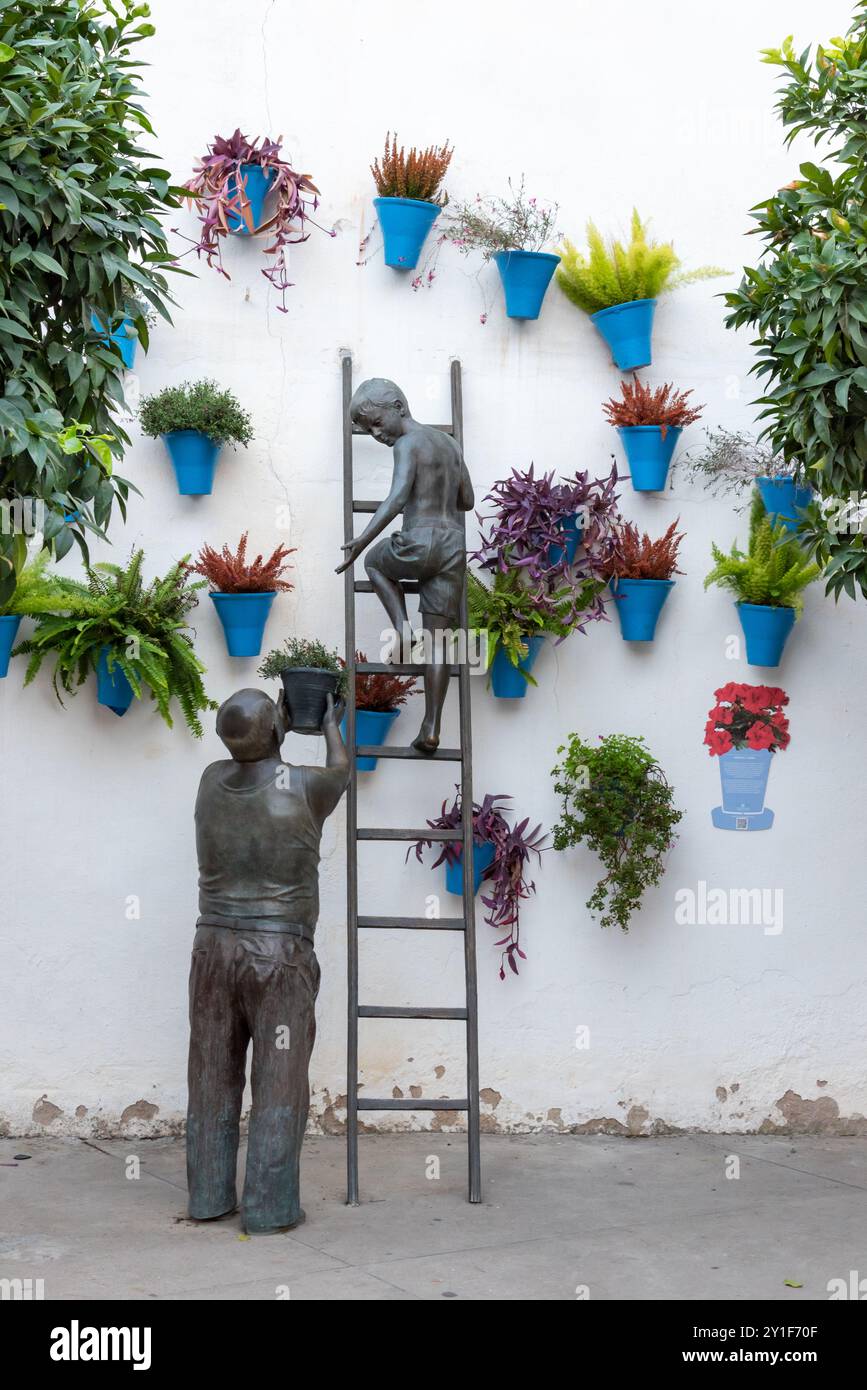 7/11/2023, Cordova; Scultura in omaggio ai proprietari e custodi dei patii di Cordova, il nonno regala un vaso di fiori al nipote da impiccare. Foto Stock