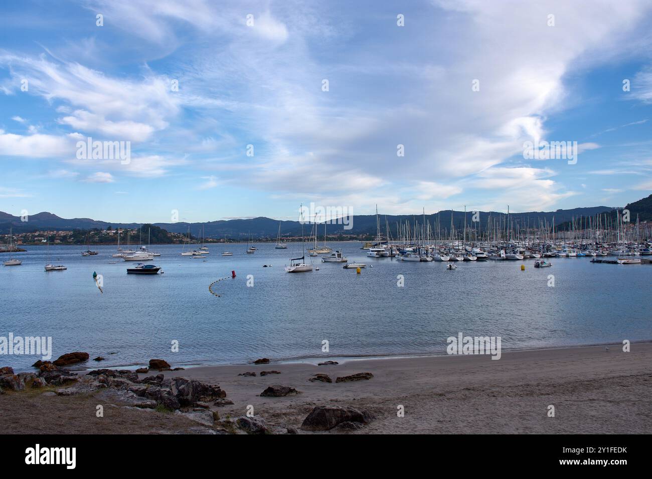 Una scena serena dalla spiaggia di Barbeira a Bayona, Pontevedra, Spagna. Le calme acque della baia sono punteggiate da barche a vela e piccoli yacht, pacificamente anc Foto Stock