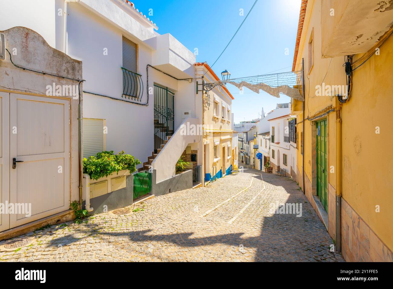 Una strada residenziale collinare che porta alla città vecchia nella storica cittadina di mare bianca di Lagos, nella regione dell'Algarve nel Portogallo meridionale. Foto Stock