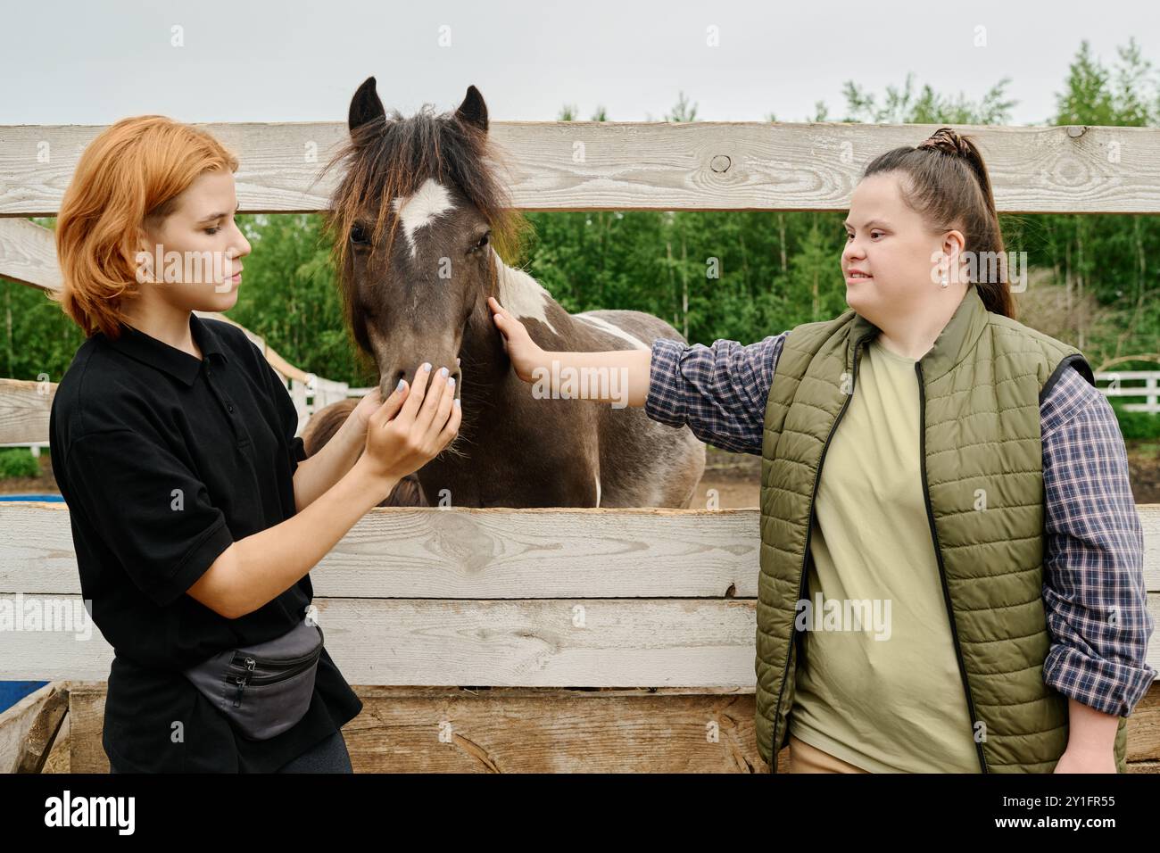 Giovani che si impegnano con un bel cavallo nel ranch all'aperto, sorridendo mentre si godono il momento e rafforzando il legame con gli animali Foto Stock