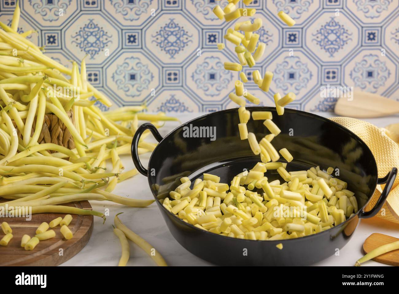 I chicchi affettati cadono in una pentola da cucina sul piano di lavoro della cucina, mentre i chicchi interi sullo sfondo Foto Stock