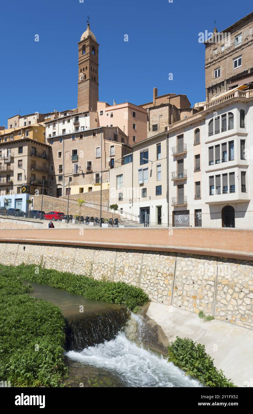 Città storica con un fiume urbano, diversi edifici e un'imponente torre sotto un cielo azzurro, chiesa, Iglesia de Santa Maria Magdalena, Rio Quei Foto Stock