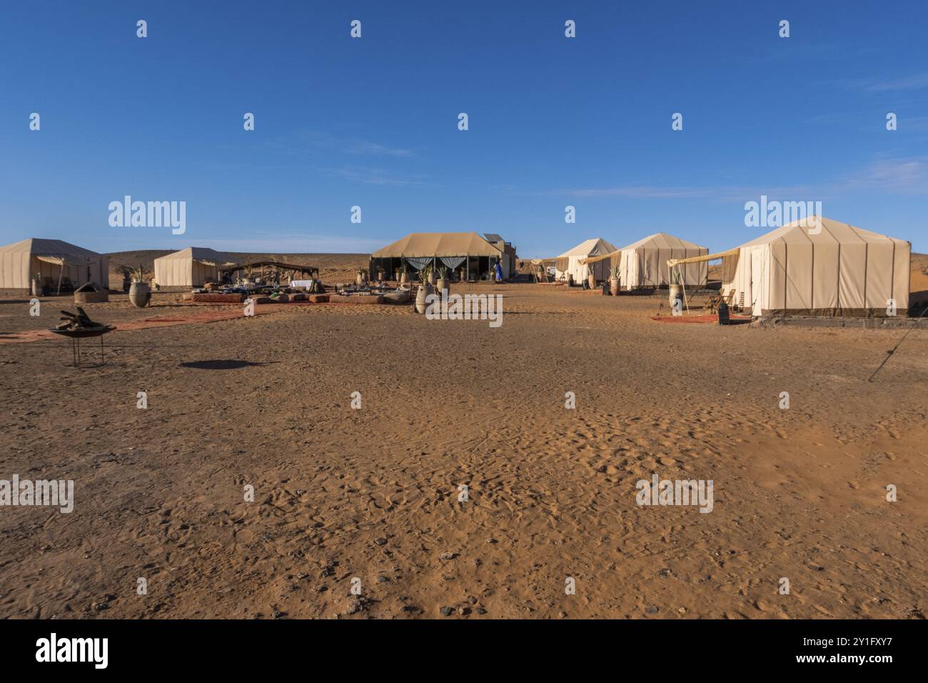 Un tradizionale campo nomade marocchino allestito nel deserto, con tende beduine, cammelli e fuochi di cucina Foto Stock