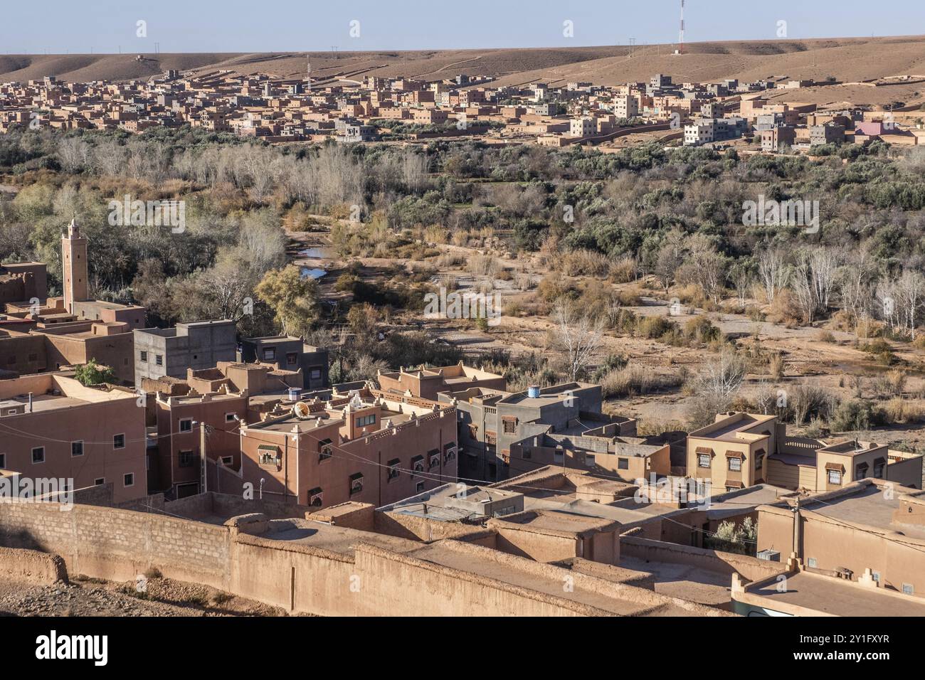 Un tradizionale villaggio berbero annidato ai piedi delle montagne dell'Atlante, con case in mattoni di fango e palmeti che punteggiano il paesaggio Foto Stock