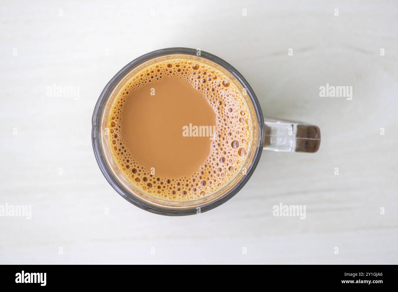 Una tazza di tè al latte caldo o di dudh cha in una tazza di vetro, vista dall'alto. Foto Stock