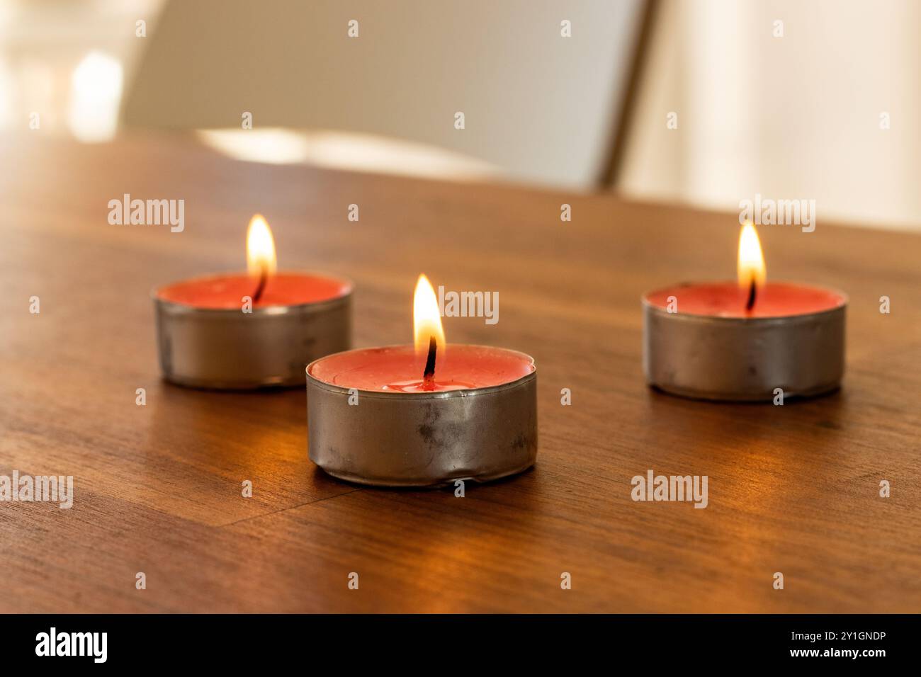 Piccole candele incandescenti poste contro la finestra Foto Stock