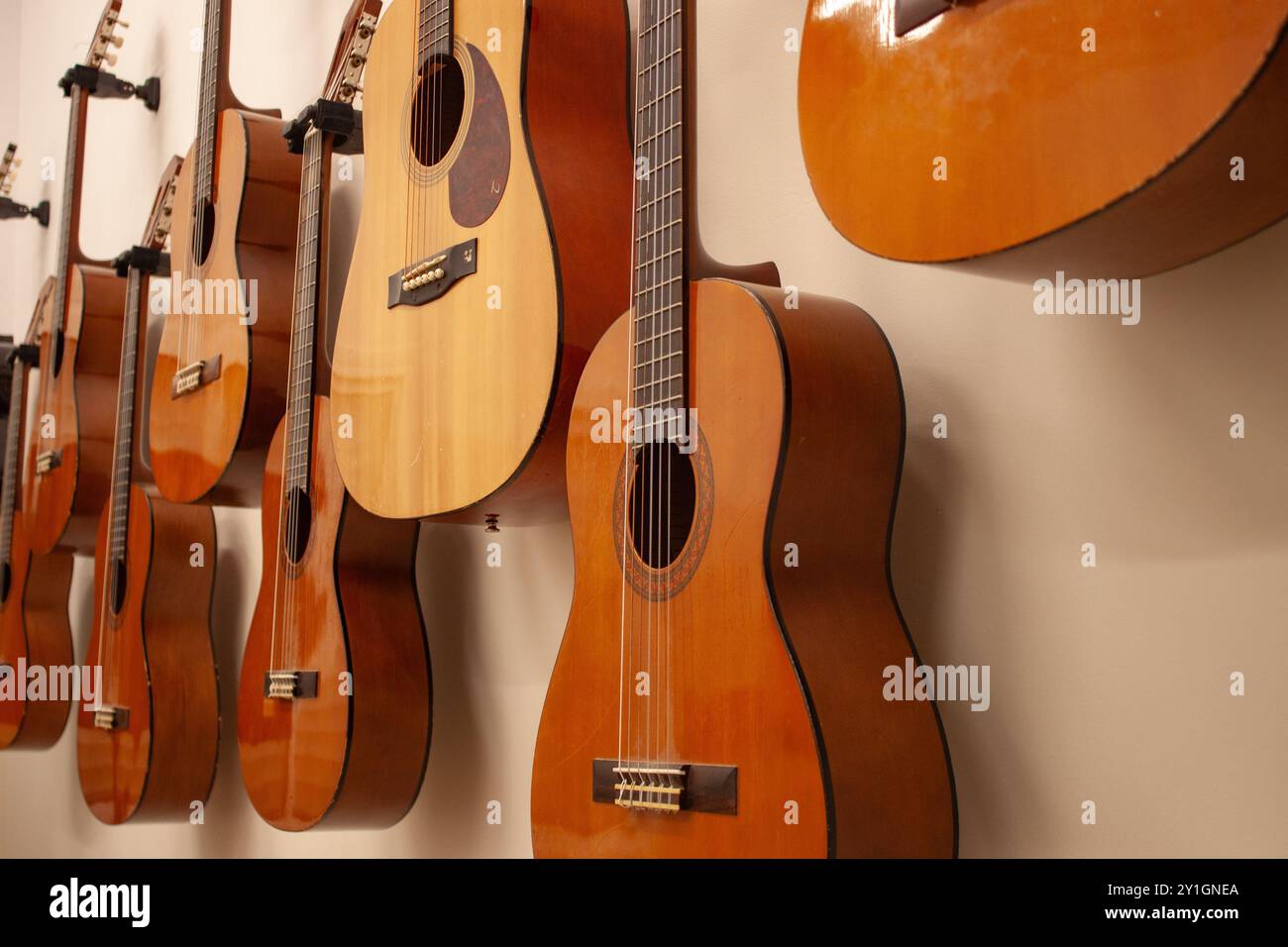 Primo piano di diverse chitarre spagnole appese al muro, dopo una lezione di musica Foto Stock
