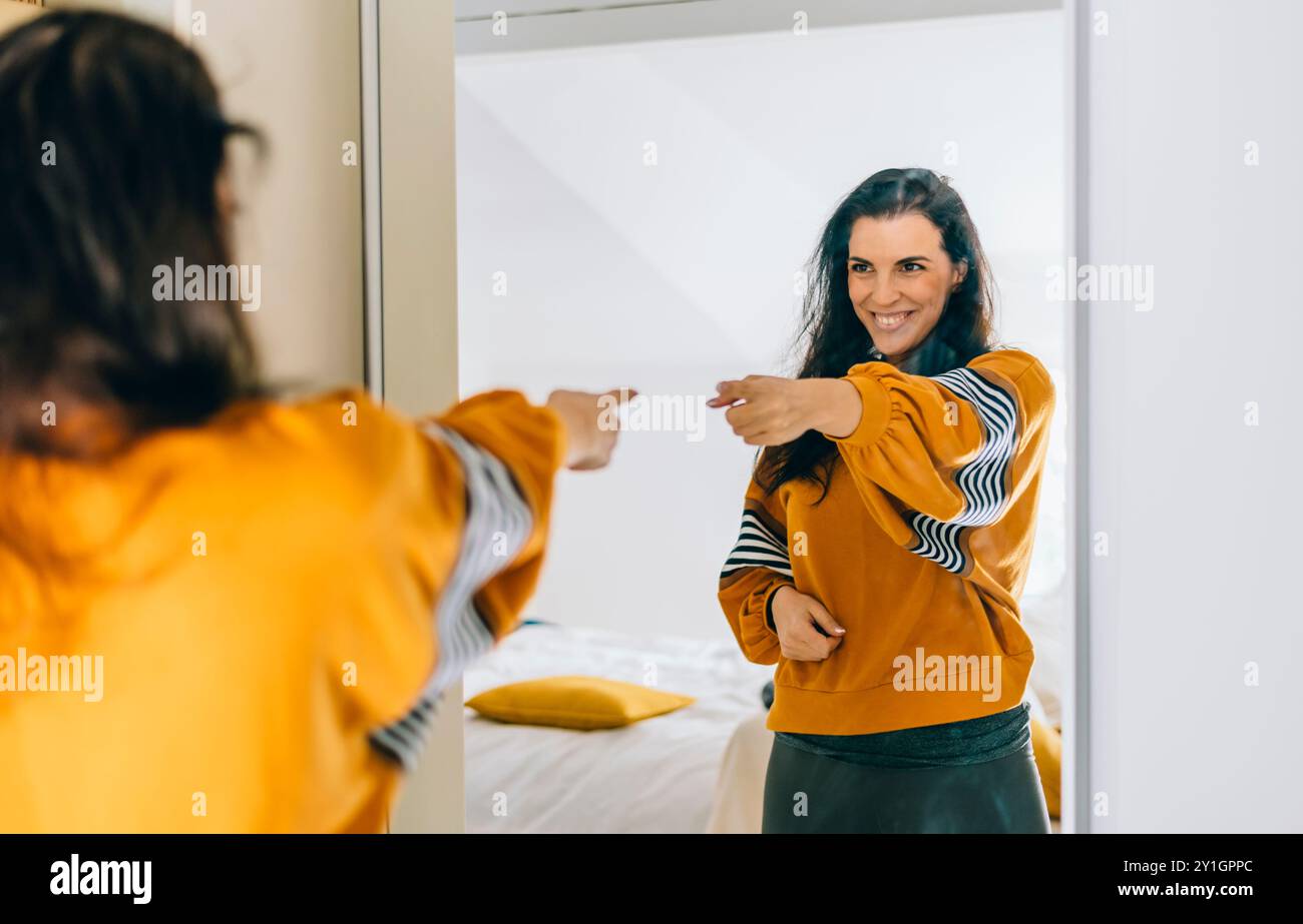 Una donna single sicura di sé che punta il dito al riflesso nello specchio che balla e abbatte bene. Una persona indipendente con un'alta autostima parla positivo Foto Stock