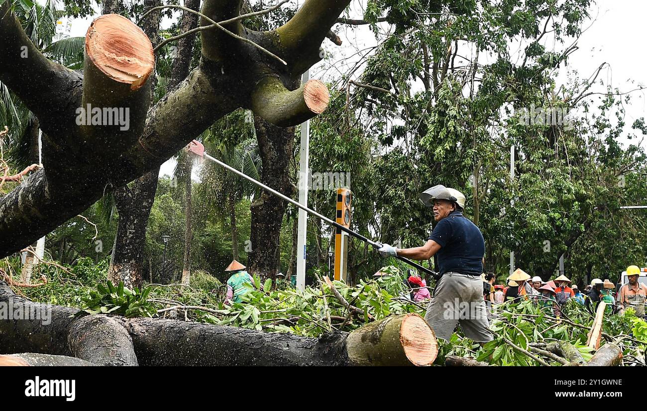 Haikou, la provincia cinese di Hainan. 7 settembre 2024. I membri del personale rimuovono un albero caduto e rami in una strada di Haikou, nella provincia di Hainan, nella Cina meridionale, 7 settembre 2024. Il Super Typhoon Yagi ha colpito la provincia dell'isola di Hainan, nella Cina meridionale, con forti piogge e venti gustosi, lasciando almeno due persone morte e 92 feriti, hanno detto le autorità locali sabato. Quando venti e piogge si placarono, Hainan diminuì il suo allarme tifone e avviò rapide operazioni di recupero in tutta la provincia. Crediti: Yang Guanyu/Xinhua/Alamy Live News Foto Stock