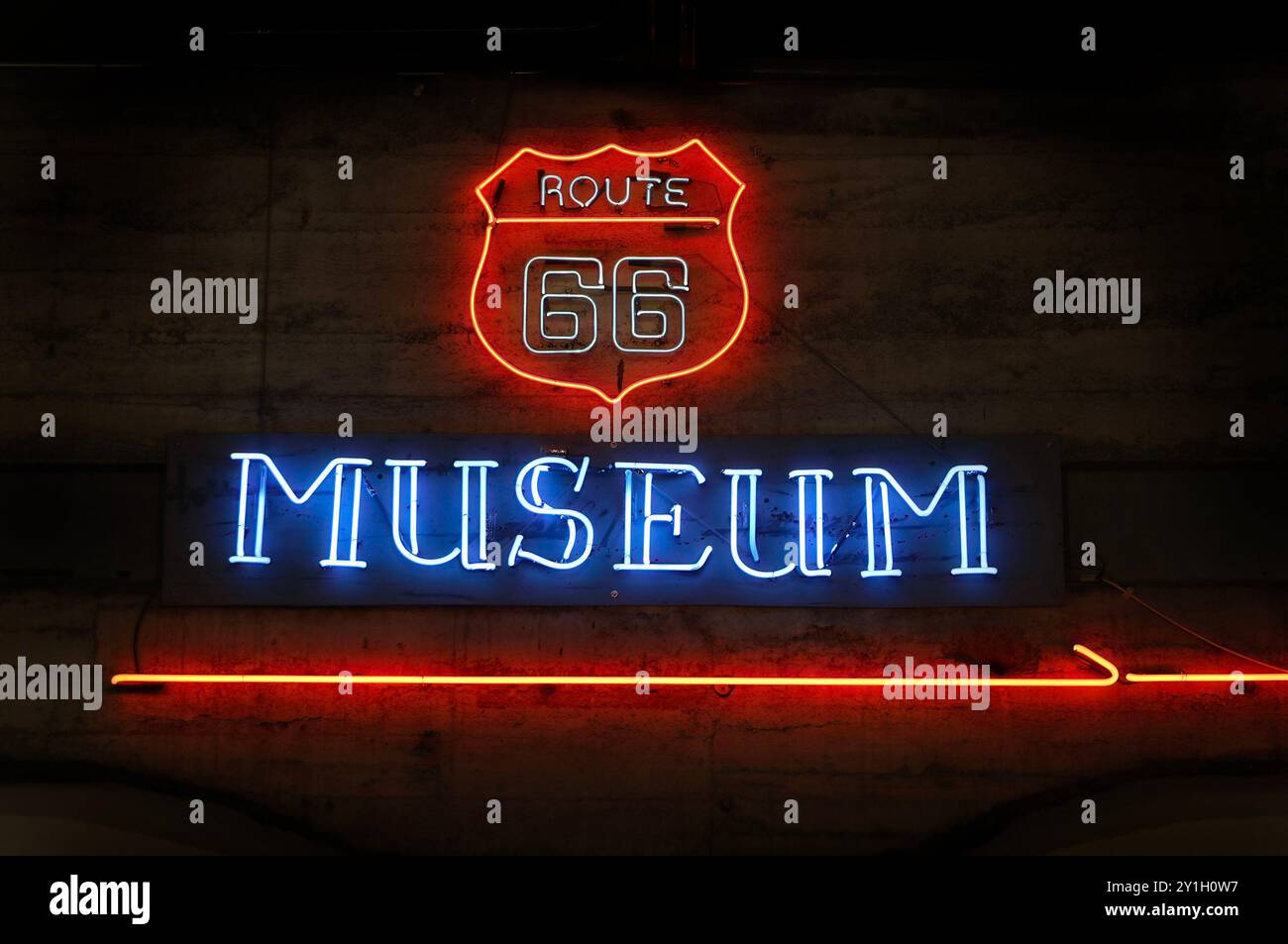 Insegne al neon illuminate della Route 66 e del museo su uno sfondo scuro che mostra le iconiche immagini della storica autostrada americana. Foto Stock