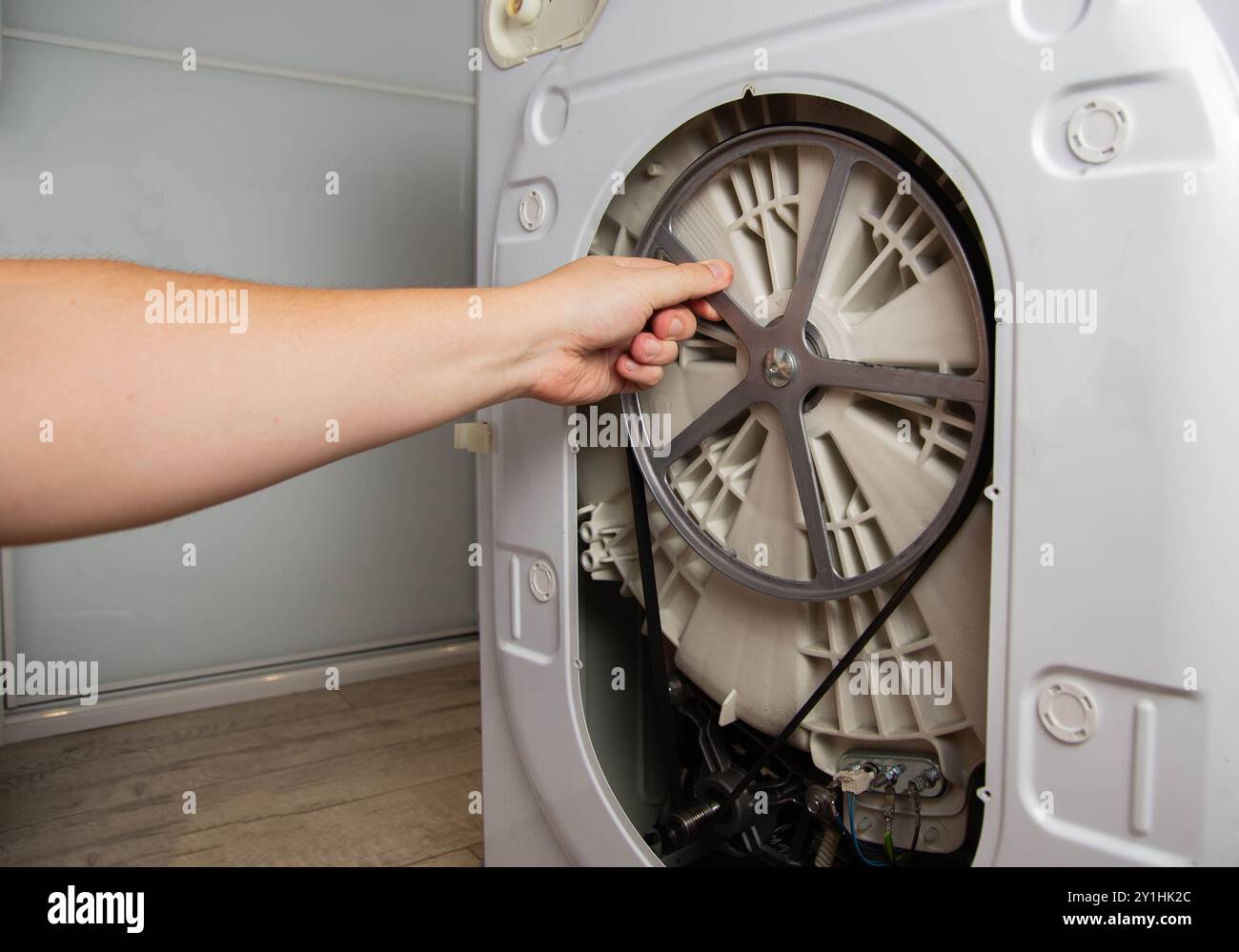 controllo della tensione della cinghia sulle pulegge della lavatrice. Guasto lavatrice, allentamento cinghia, industria Foto Stock