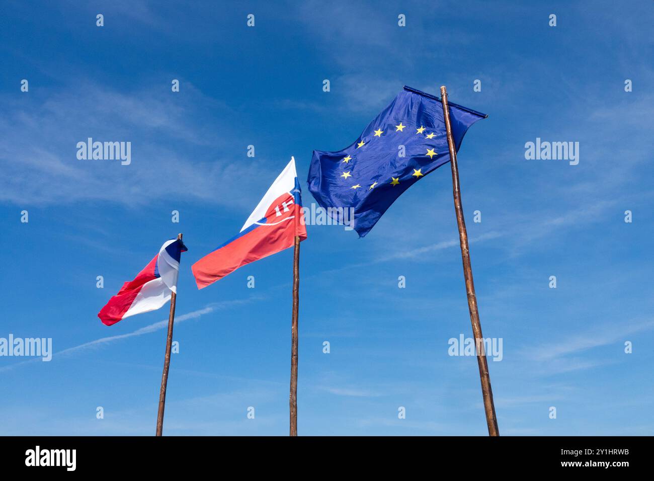 La bandiera dell'Unione europea, la bandiera della Slovacchia e la bandiera ceca, soffiano ondulazioni e sventolano nel vento su bandiere di legno contro il cielo blu Foto Stock