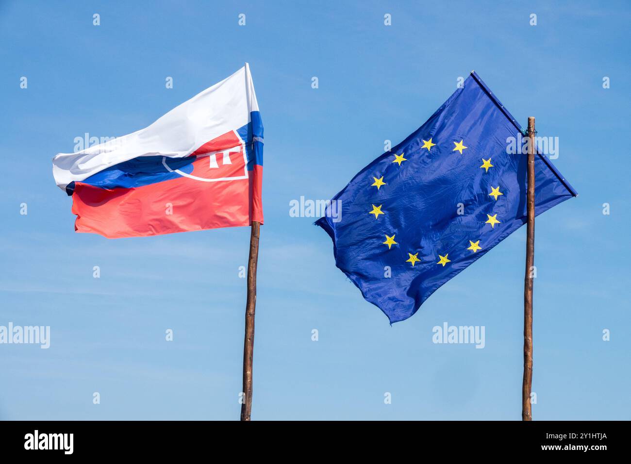 Bandiera della Slovacchia e bandiera dell'Unione europea che soffia nel vento su bandiere a palo di legno Foto Stock