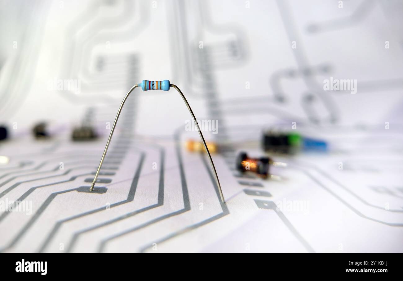Resistore elettrico singolo su sfondo sfocato degli schemi. Concetto di progettazione, progettazione e produzione di sistemi elettronici. Concentrata sui resi Foto Stock
