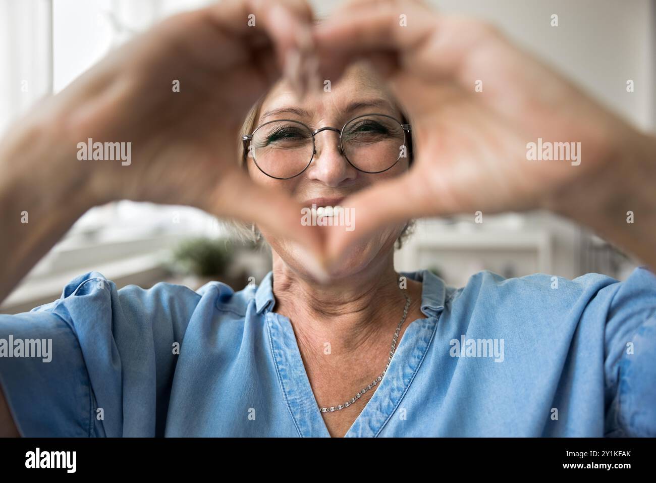 La donna indossa occhiali che mostrano il simbolo del cuore alla macchina fotografica Foto Stock
