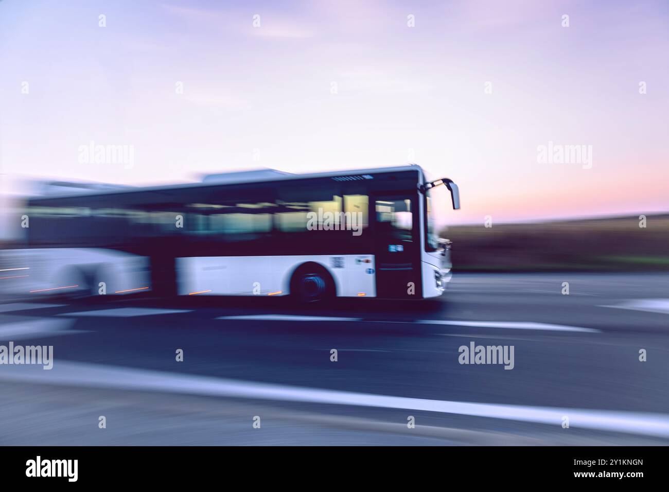 Un autobus che si muove velocemente sulla strada al tramonto, con movimenti intenzionali di panning sfocati. Foto Stock