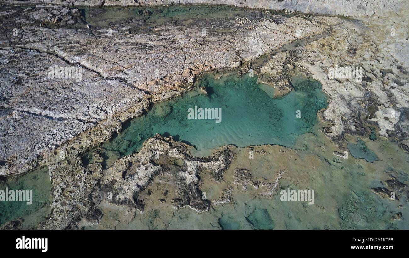 Colpo di droni, primo piano di rocce e acque turchesi con crepe e forme geologiche chiare, Gramvoussa, penisola di Gramvoussa, Baia dei Pirati, Balos, laguna Foto Stock