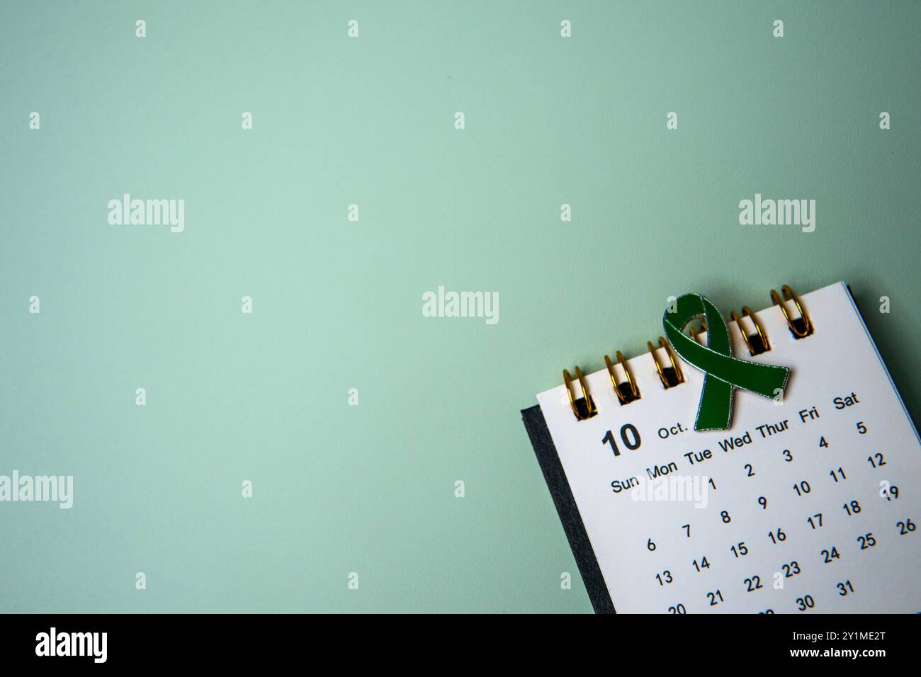 Un calendario aperto al mese di ottobre e un nastro verde che simboleggia la consapevolezza della salute mentale. Copia spazio per il testo. Foto Stock