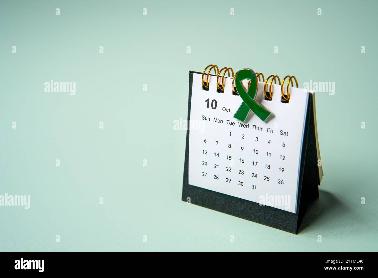 Un calendario aperto al mese di ottobre e un nastro verde che simboleggia la consapevolezza della salute mentale. Copia spazio per il testo. Foto Stock