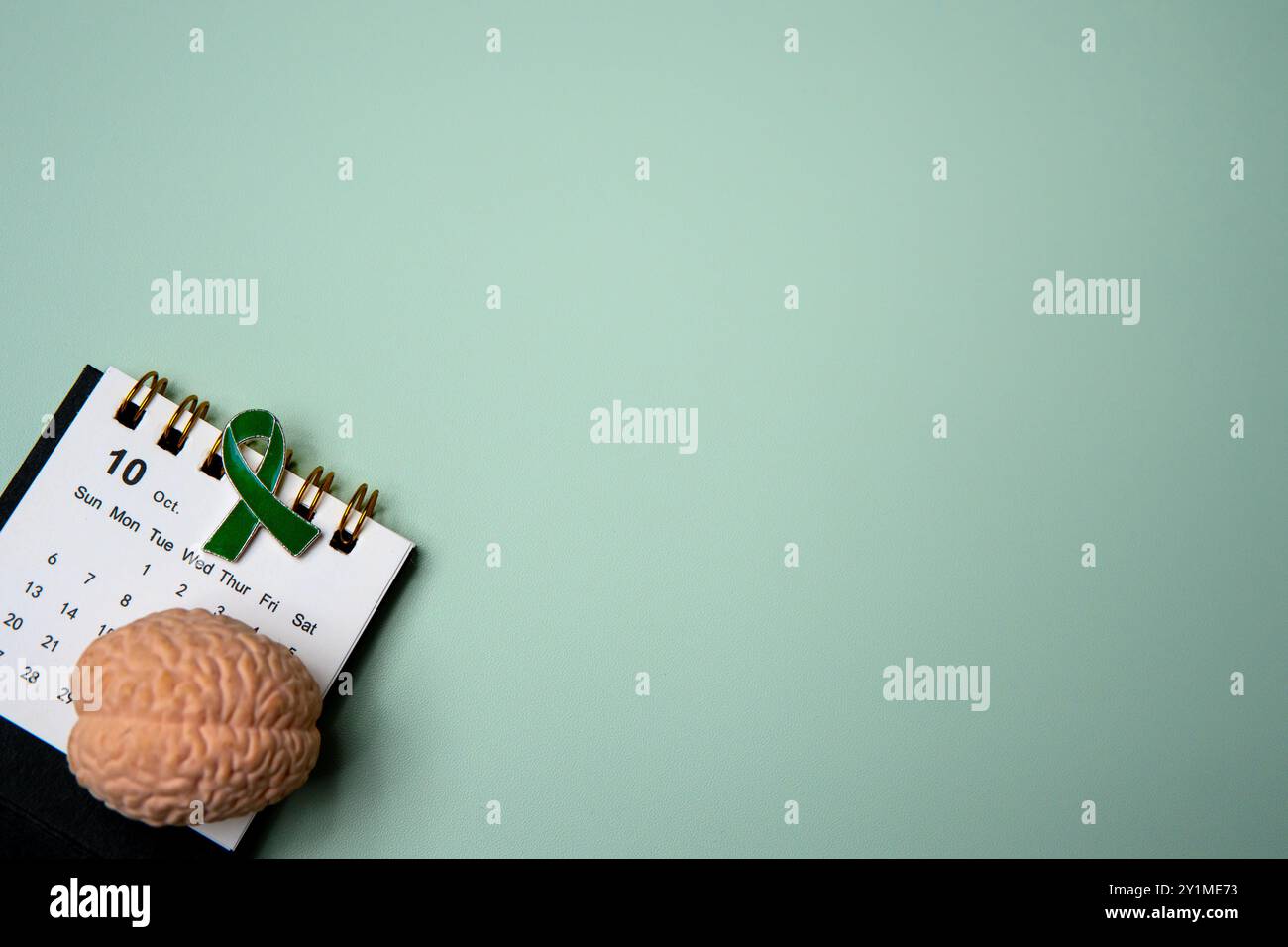 Un calendario aperto al mese di ottobre e un nastro verde che simboleggia la consapevolezza della salute mentale. Copia spazio per il testo. Foto Stock
