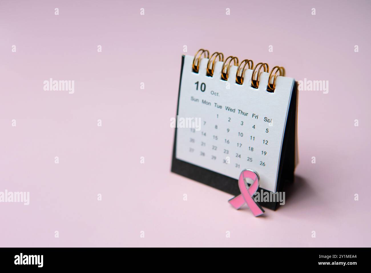 Un calendario aperto al mese di ottobre e un nastro rosa, che simboleggia la consapevolezza del cancro al seno. Copia spazio per il testo. Foto Stock