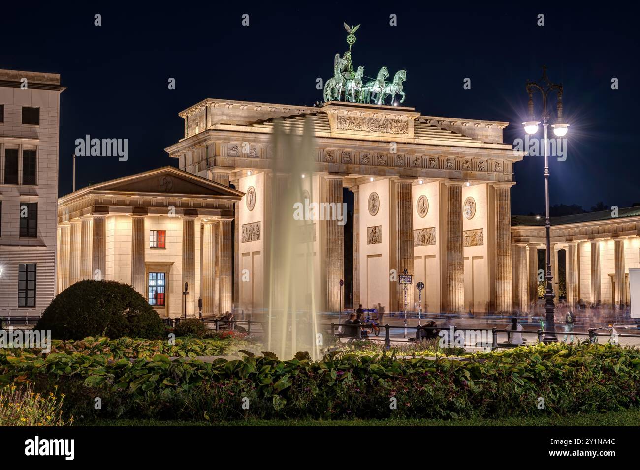 La porta di Brandeburgo illuminata di Berlino con una fontana di notte Foto Stock