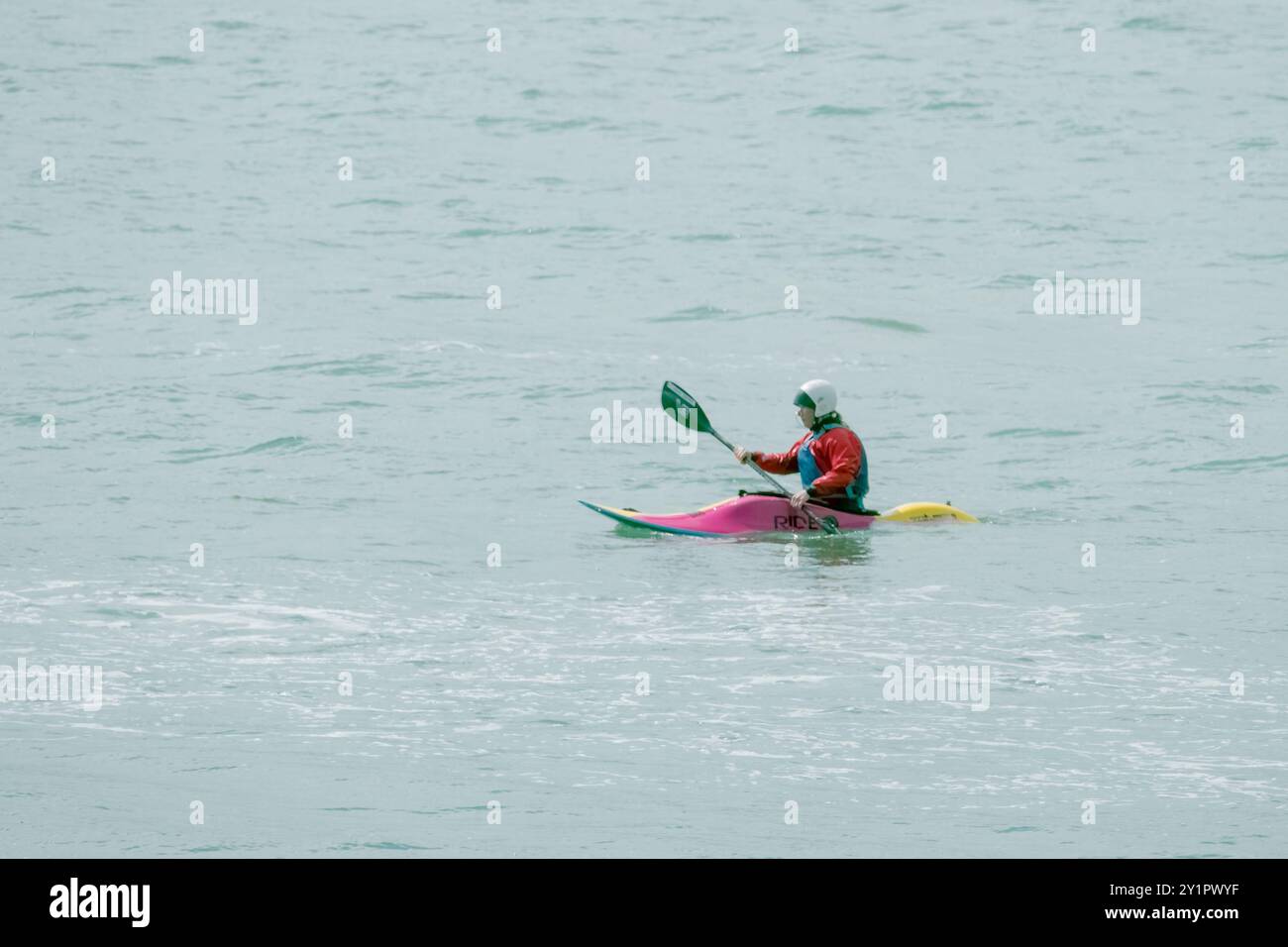 West Cork, Irlanda, 22 aprile 2023. Un kayak solitario naviga sull'acqua liscia a bordo di un kayak dai colori vivaci, godendoti l'atmosfera serena. Foto Stock