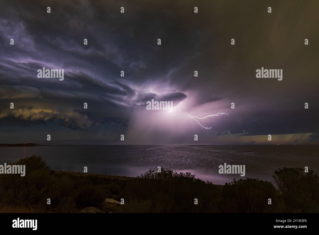 Un fulmine lampeggia e si riflette sulle nuvole e sulla superficie del grande Lago Salato vicino a Syracuse, Davis County, Utah, USA. Foto Stock