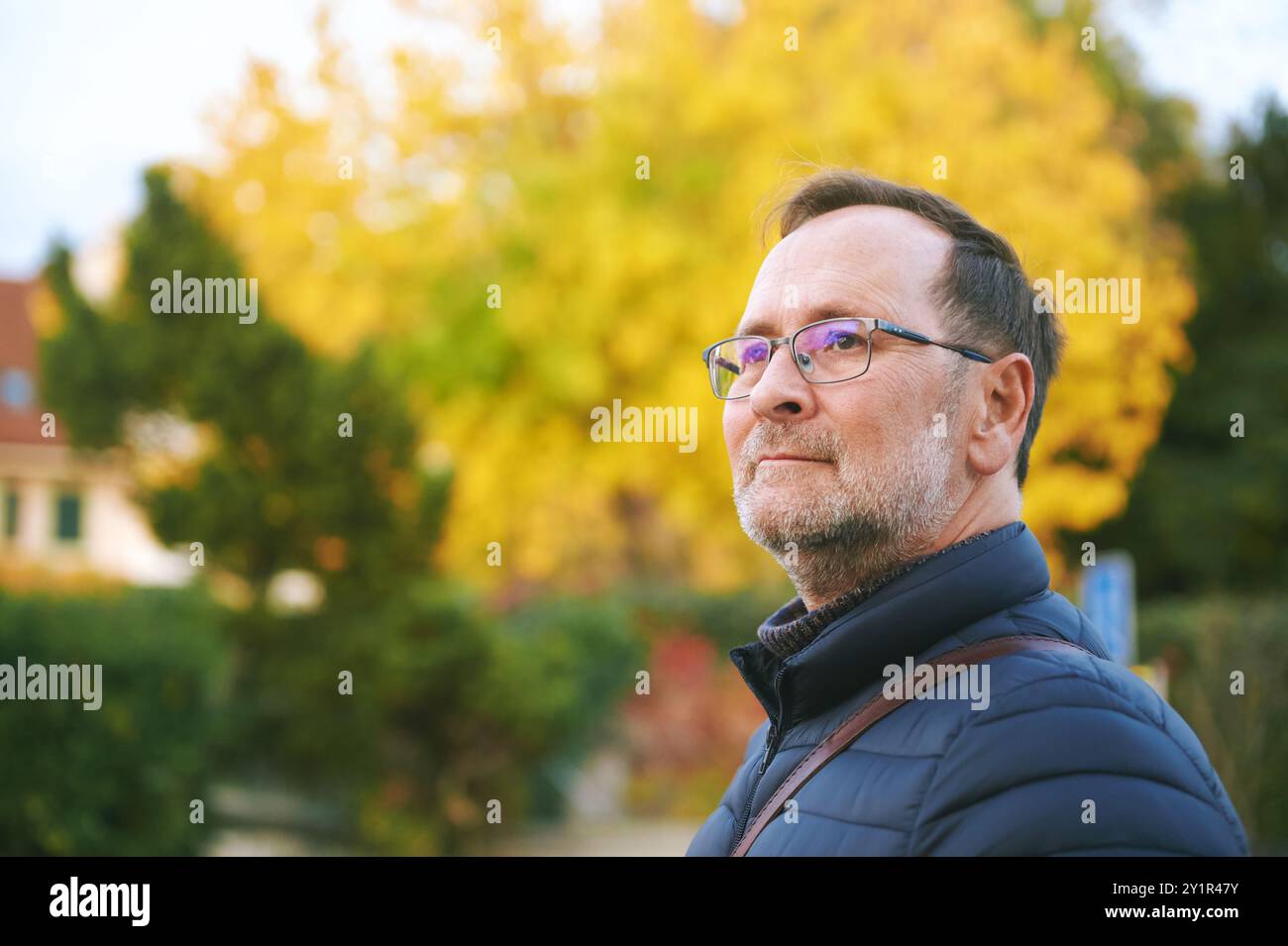 Ritratto autunnale di un bell'uomo di 50 anni che posa all'aperto con sfondo giallo fogliame Foto Stock