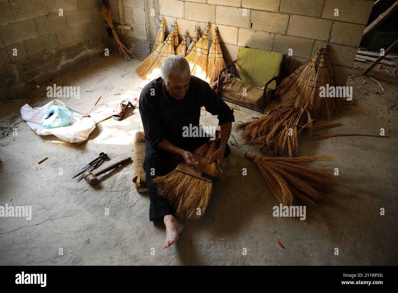 Cisgiordania, Palestina. 27 settembre 2019. Sobhi Jaradat, 57 anni, produce scopa di paglia da quasi 15 anni nel villaggio di Zububa, nel governatorato di Jenin. Per produrre le scope, Jaradat utilizza un tipo speciale di mais, che viene coltivato dagli agricoltori locali dall'inizio di aprile e richiede cure fino alla fine di luglio. I gambi di mais vengono raccolti, puliti dai semi e poi portati all'artigiano che crea le spazzatrici. In Palestina, l'arte di fare scopa con la paglia è stata tramandata da generazioni e conservata da pochi abili artigiani come Sobhi Foto Stock