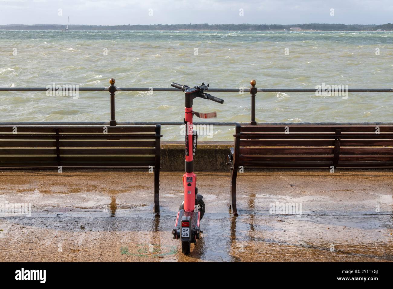 Voi. l'e-scooter è stato abbandonato da solo sul lungomare in una giornata di pioggia. Scooter elettrico solitario lasciato al mare il giorno della pioggia. Foto Stock