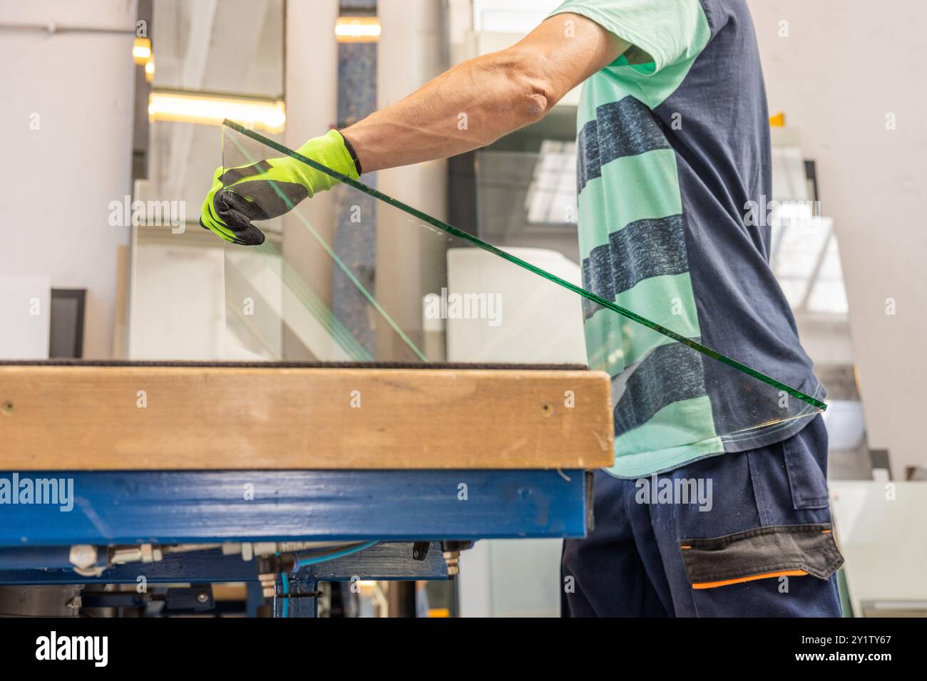 Un vetraio posiziona le lastre di vetro su un tavolo specializzato. Il concetto di artigianato e industria. Lavorare con il vetro. Foto Stock