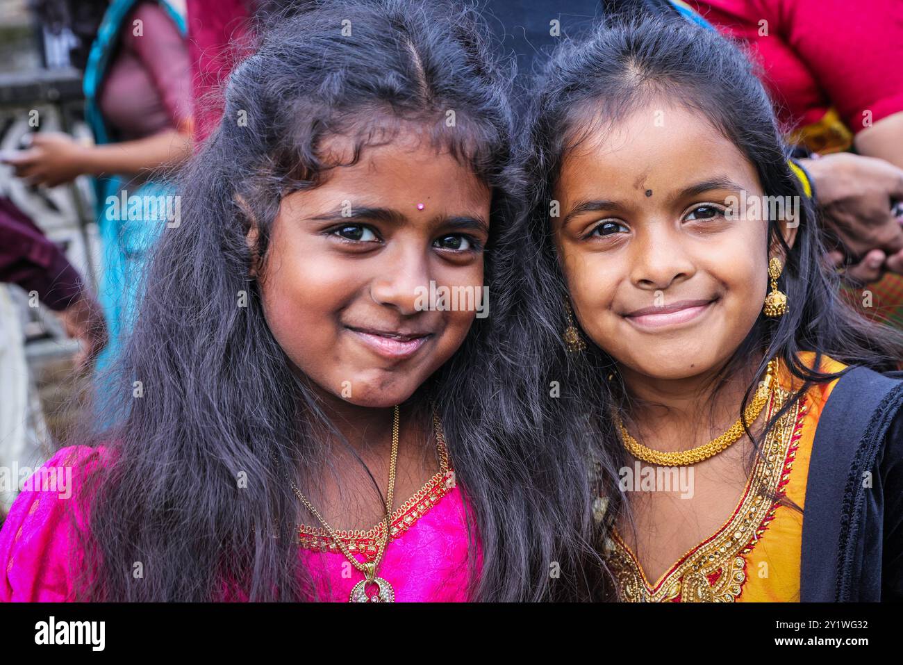 Londra, Regno Unito. 8 settembre 2024. Due ragazze sorridono e frequentano i genitori e i fratelli. Diverse migliaia di devoti della comunità Tamil prendono parte all'annuale Festival dei carri (Ter) dal tempio di Sivan Kovil per le strade di Lewisham. Le divinità di Ganesha e Lord Shiva sono trasportate in carri decorati. I devoti fanno offerte di latte, incenso bruciato, noci di cocco o frutta. Crediti: Imageplotter/Alamy Live News Foto Stock