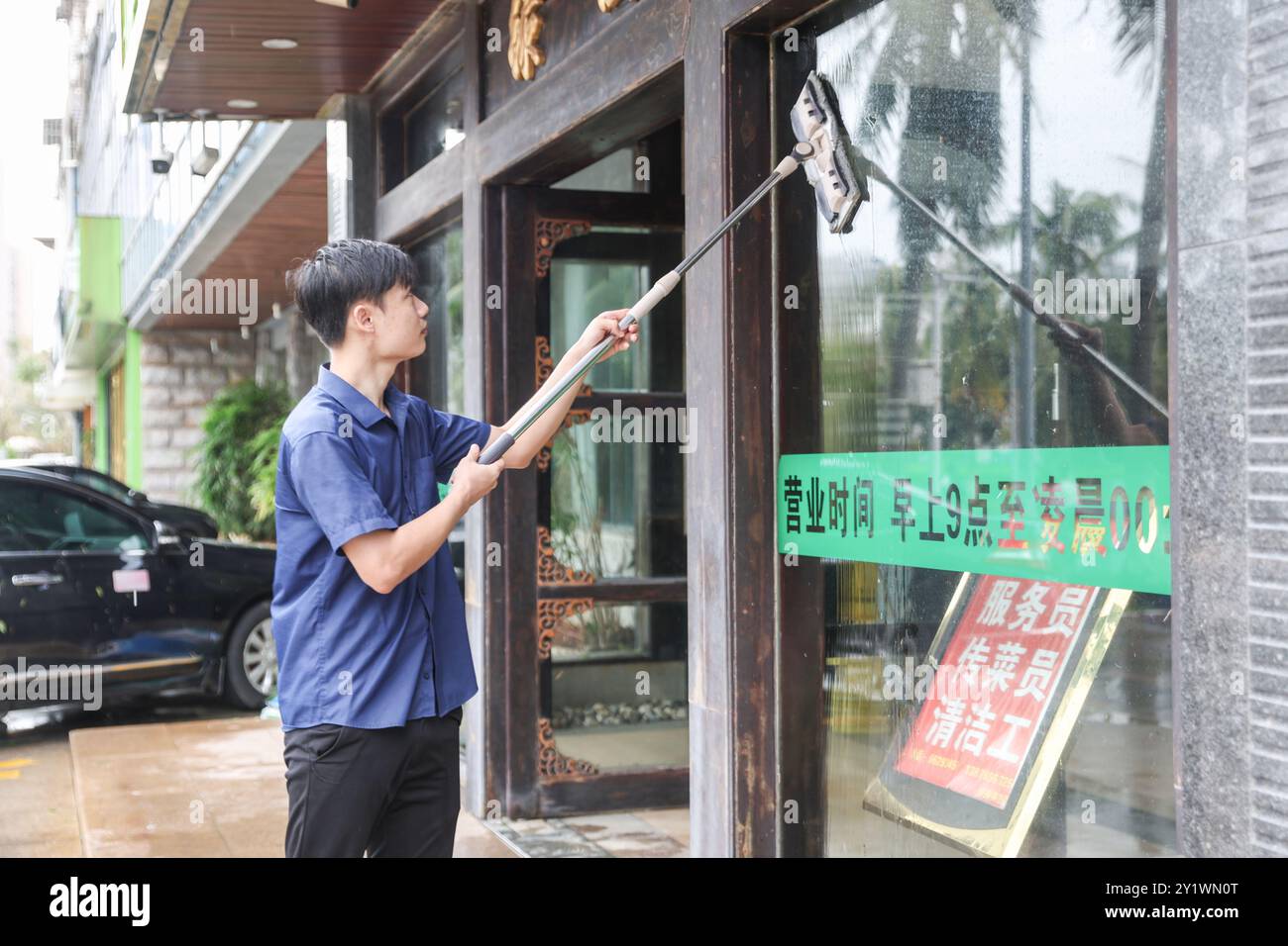 Haikou, la provincia cinese di Hainan. 7 settembre 2024. Un uomo pulisce la finestra di un ristorante ad Haikou, nella provincia di Hainan, nella Cina meridionale, 7 settembre 2024. Yagi, l'undicesimo tifone dell'anno, sbarcò a Hainan il venerdì pomeriggio. Quando venti e piogge si placarono, Hainan diminuì il suo allarme tifone e avviò rapide operazioni di recupero in tutta la provincia. Crediti: Zhang Liyun/Xinhua/Alamy Live News Foto Stock