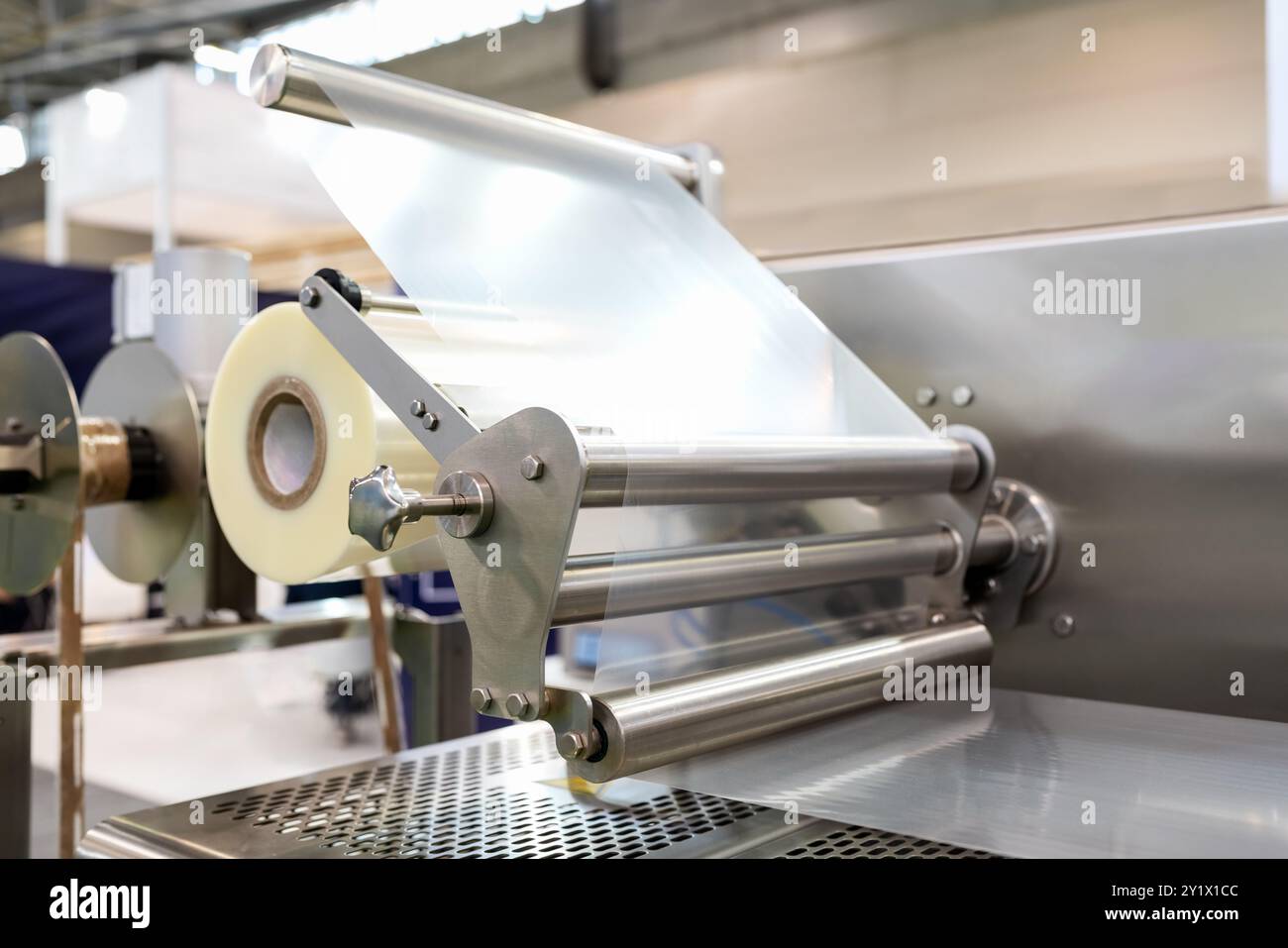 Primo piano del rotolo di pellicola plastica industriale in macchinari per imballaggio. Pellicola di polietilene. Foto Stock