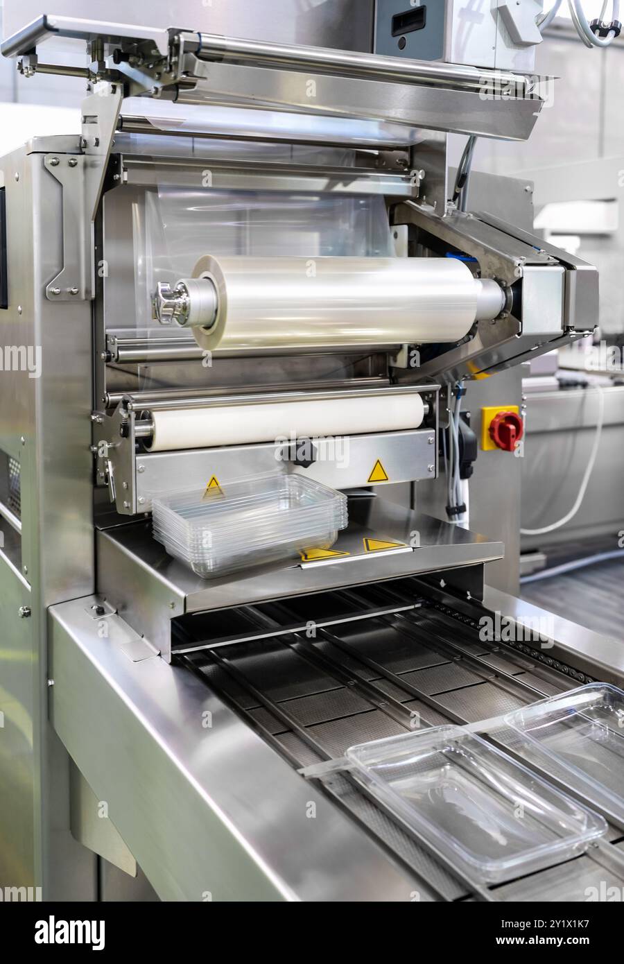 Primo piano del rotolo di pellicola plastica industriale in macchinari per imballaggio. Foto Stock