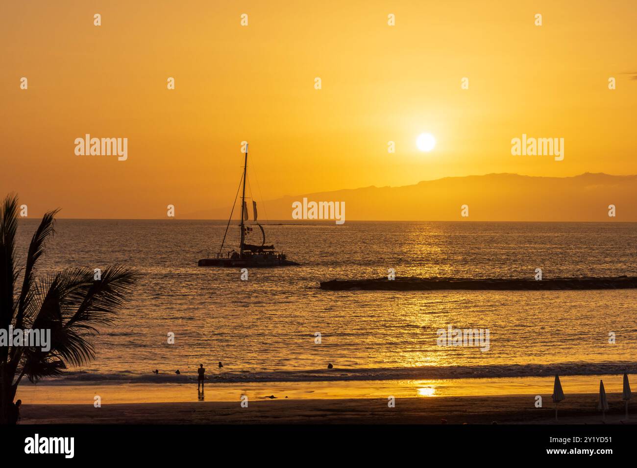 Ein Segelkatamaran im atlantischen Ozean zwischen Teneriffa und la Plama an der Küste von Costa Adeje während eines orangenen Sonnenuntergangs. Foto Stock