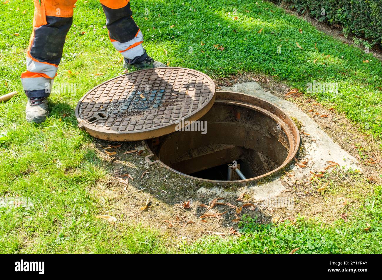 Un ouvrier enlève la plaque d'égoût pour détecter les fuites d'eau dans les canalizations de Distribution. Il pose des Instruments de mesurent Capable Foto Stock