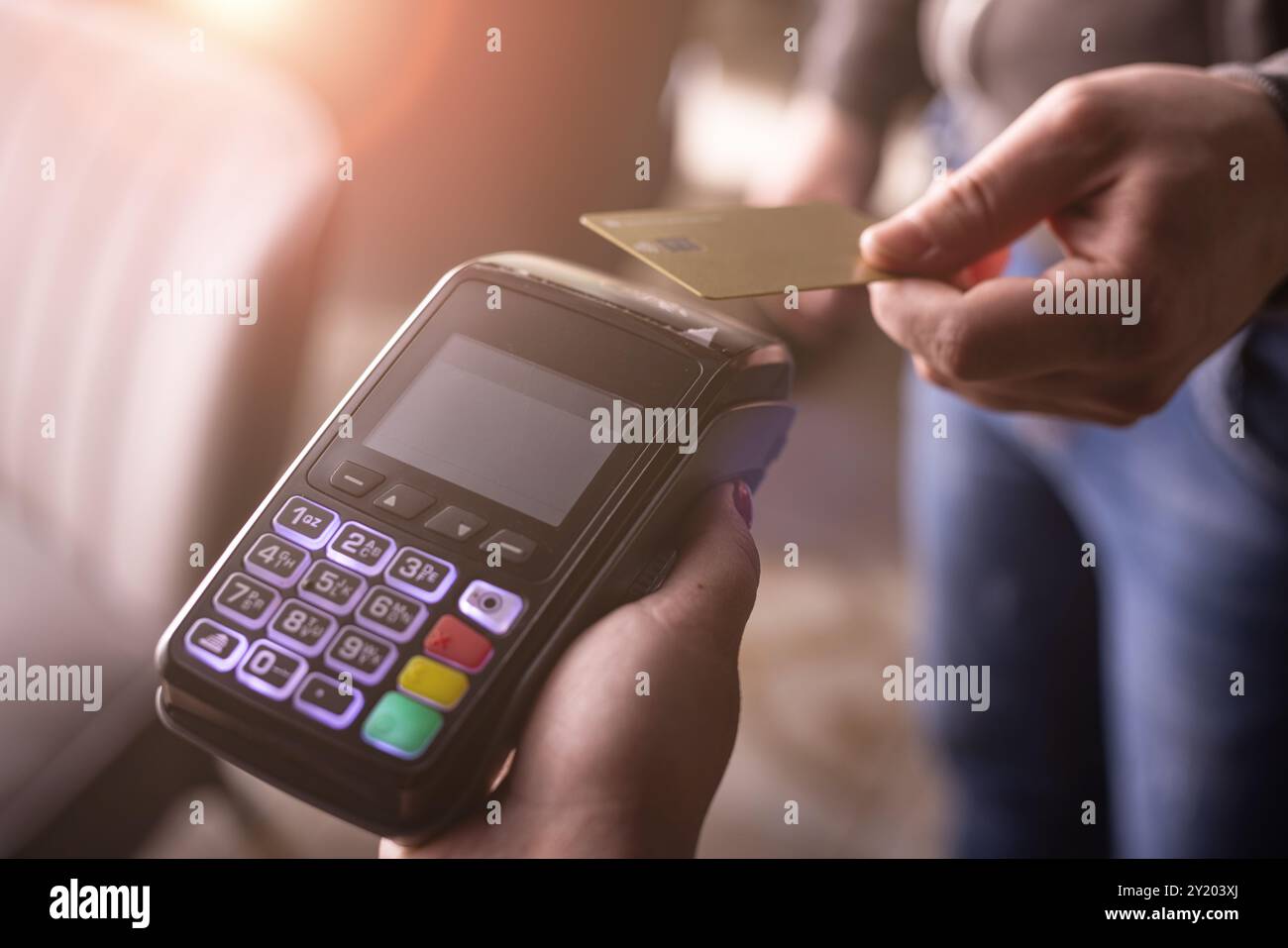 Pagamento con carta di credito NFC. Donna che paga con carta di credito contactless con tecnologia NFC. Transazione di denaro wireless. Macchina per carte in mano maschile su Sunli Foto Stock