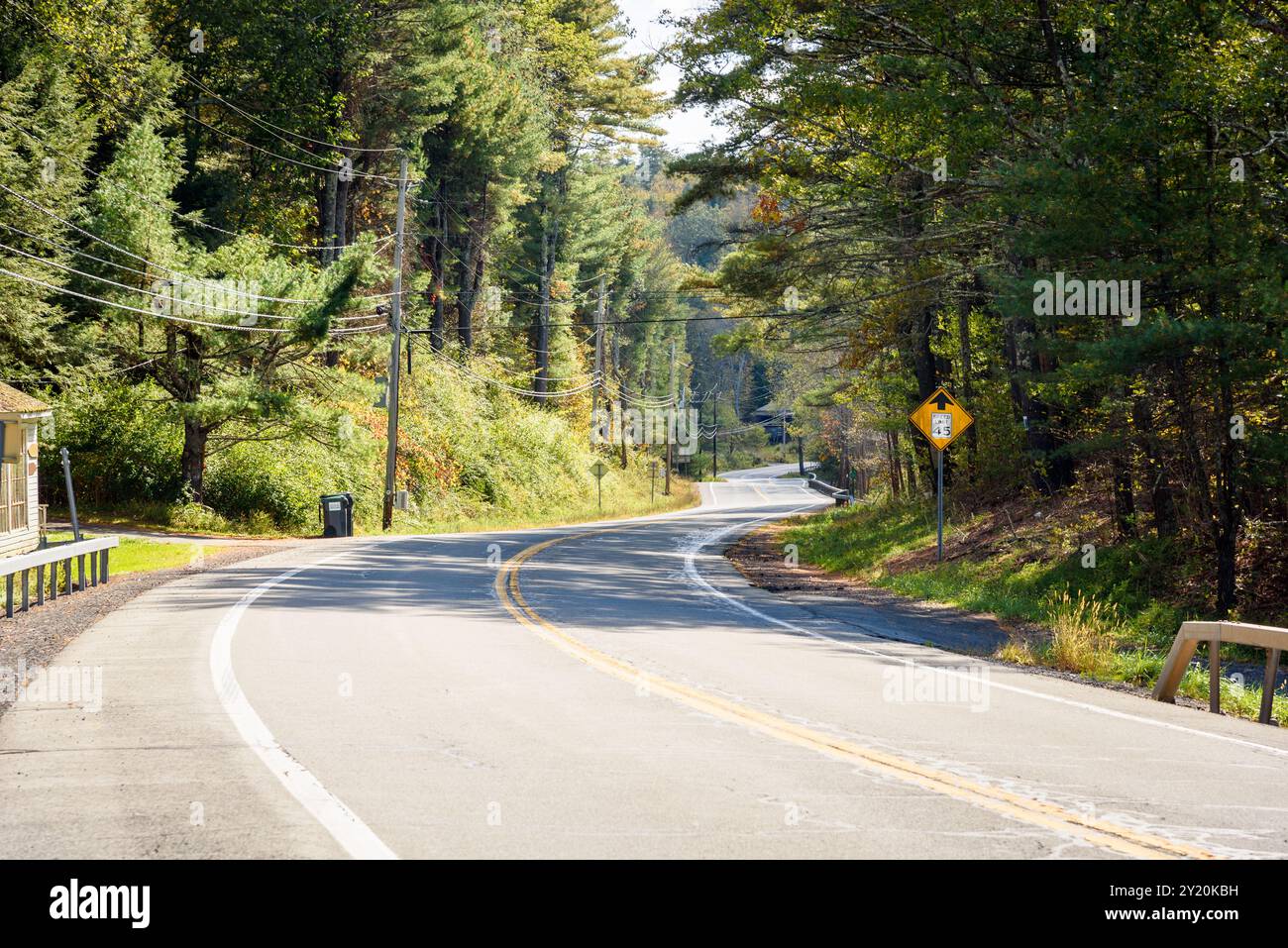 Una tortuosa strada di montagna vuota attraverso una foresta in una giornata di sole autunnale Foto Stock