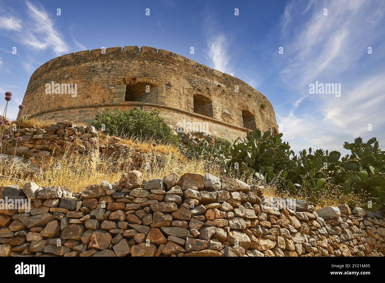 Una vecchia torre rotonda su una collina con cactus e un cielo azzurro, la Fortezza del Mare di Venezia, l'isola di Leper, Spinalonga, la baia di Elounda, baia di Mirabello, Creta Est Foto Stock